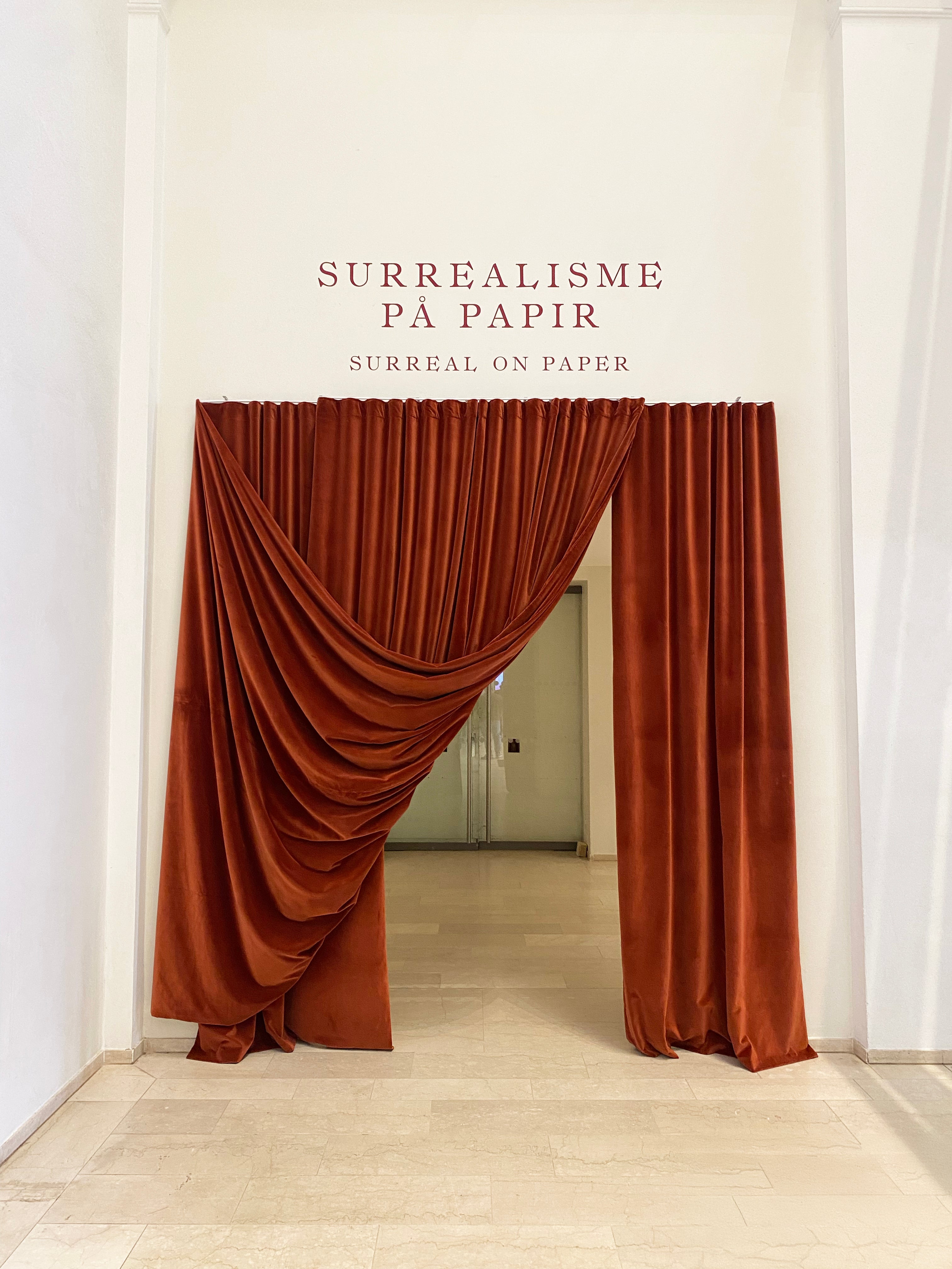 Rich terracotta velvet curtain handcrafted by Winther Wackerhausen for the SMK exhibition ‘Surrealisme på Papir,’ highlighting sculptural draping and bespoke textile design