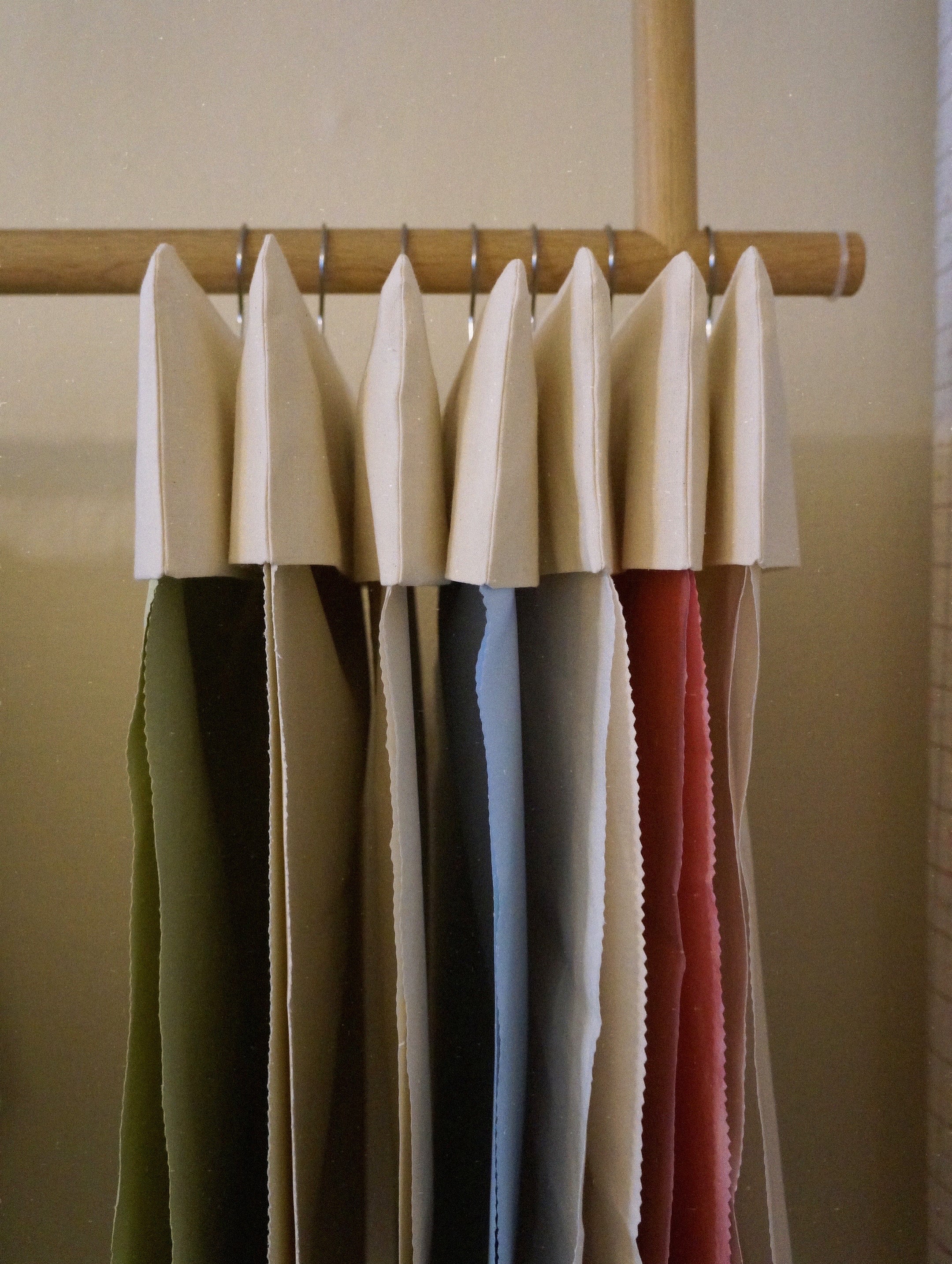 Fabric samples in multiple colours hanging neatly on a wooden rack, showcasing material options for bespoke handmade curtains.

bespoke curtains, fabric samples, custom curtain materials, handmade curtains