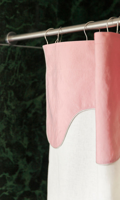 Detail view of the Winther Wackerhausen Drizzle shower curtain showing the soft pink scalloped top layer and textured white curtain fabric, styled on a chrome shower rod