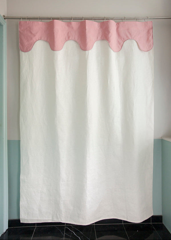Winther Wackerhausen Drizzle shower curtain featuring a soft pink scalloped top layer and a linen-textured white body, shown hanging in a minimal bathroom interior